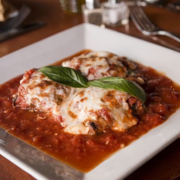Two portions of Mama Mia 44SW's eggplant parmesan, topped with melted cheese, basil, and marinara sauce.