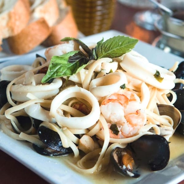 Mama Mia 44SW's linguine pasta with calamari, mussels, clams, and shrimp, garnished with basil.