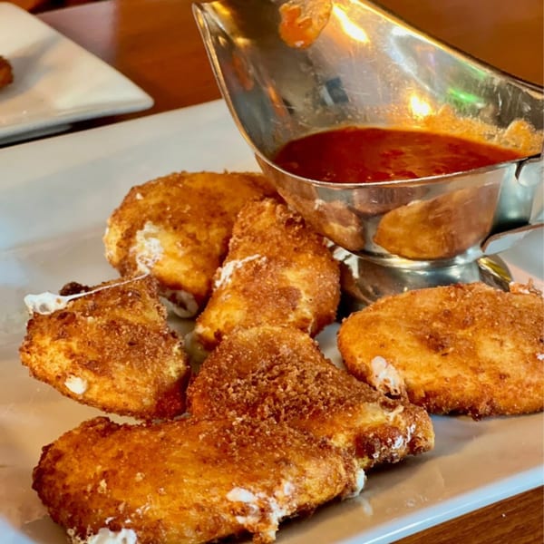 Golden-brown fried mozzarella triangles with melted cheese, served with a side of red marinara sauce.