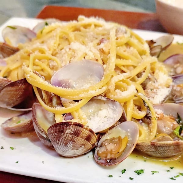 Mama Mia 44SW's linguine alle vongole, featuring pasta, clams, and parmesan cheese on a white plate.
