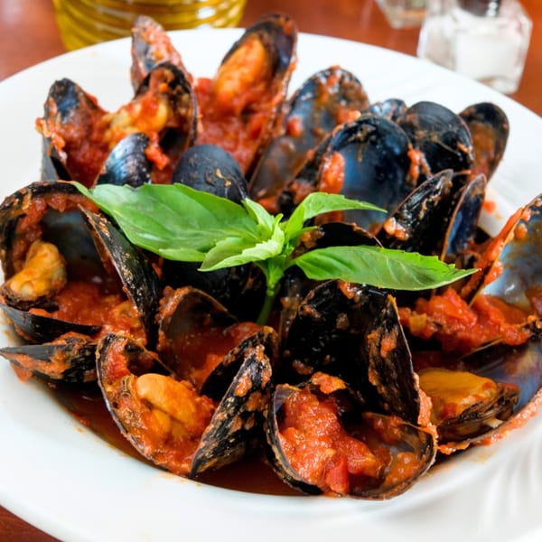 Steamed mussels in a rich red tomato sauce, garnished with fresh basil, served at Mama Mia 44SW.